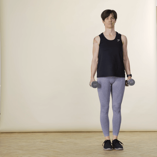 A woman in sports clothing demonstrating a weighted side lunge