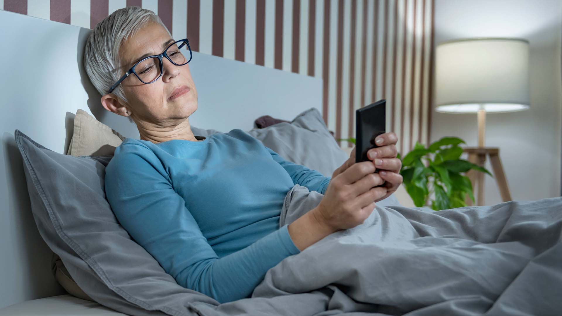Woman laying in bed looking at her mobile phone.