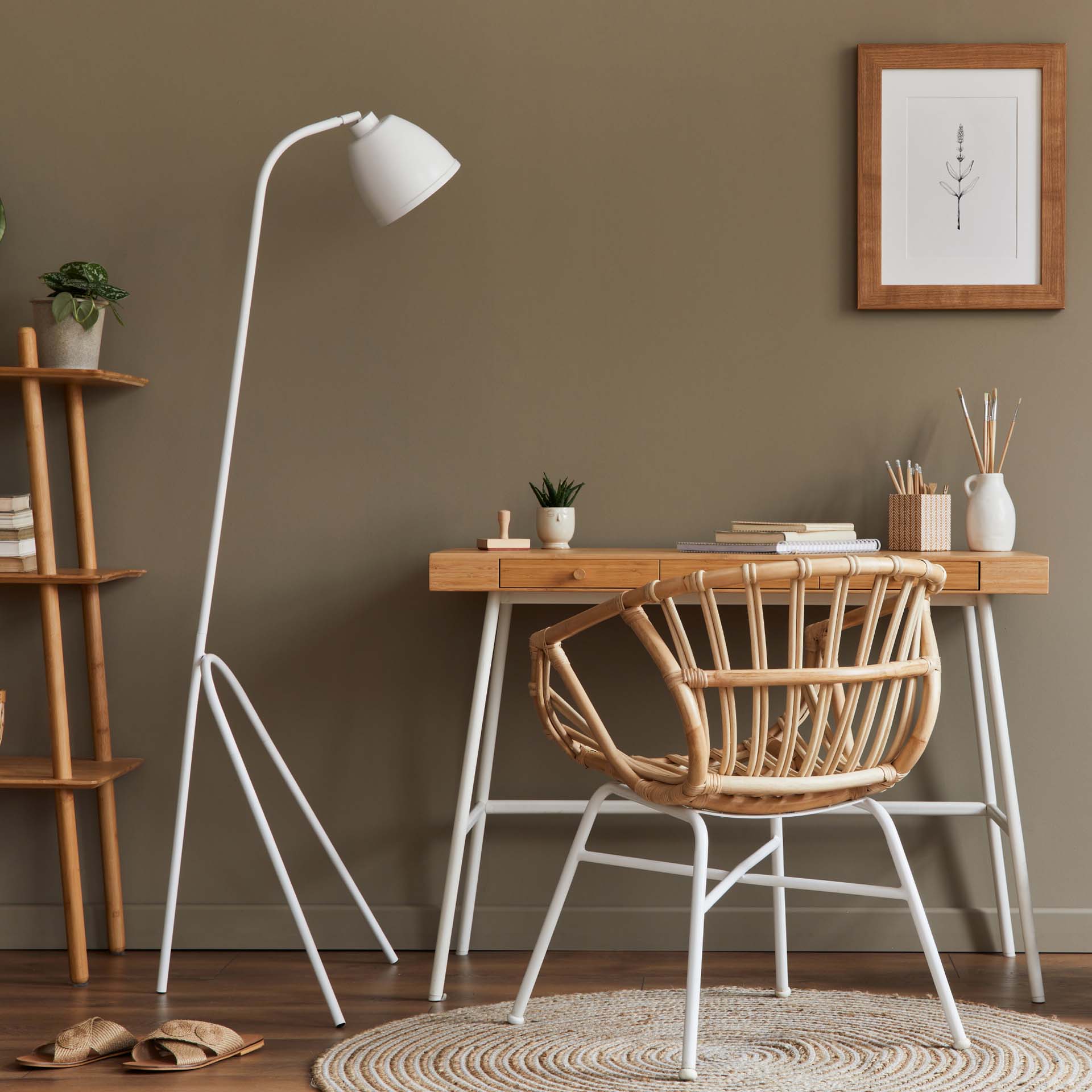 A small wooden desk with white metal legs, a matching desk chair and white standing desk lamp