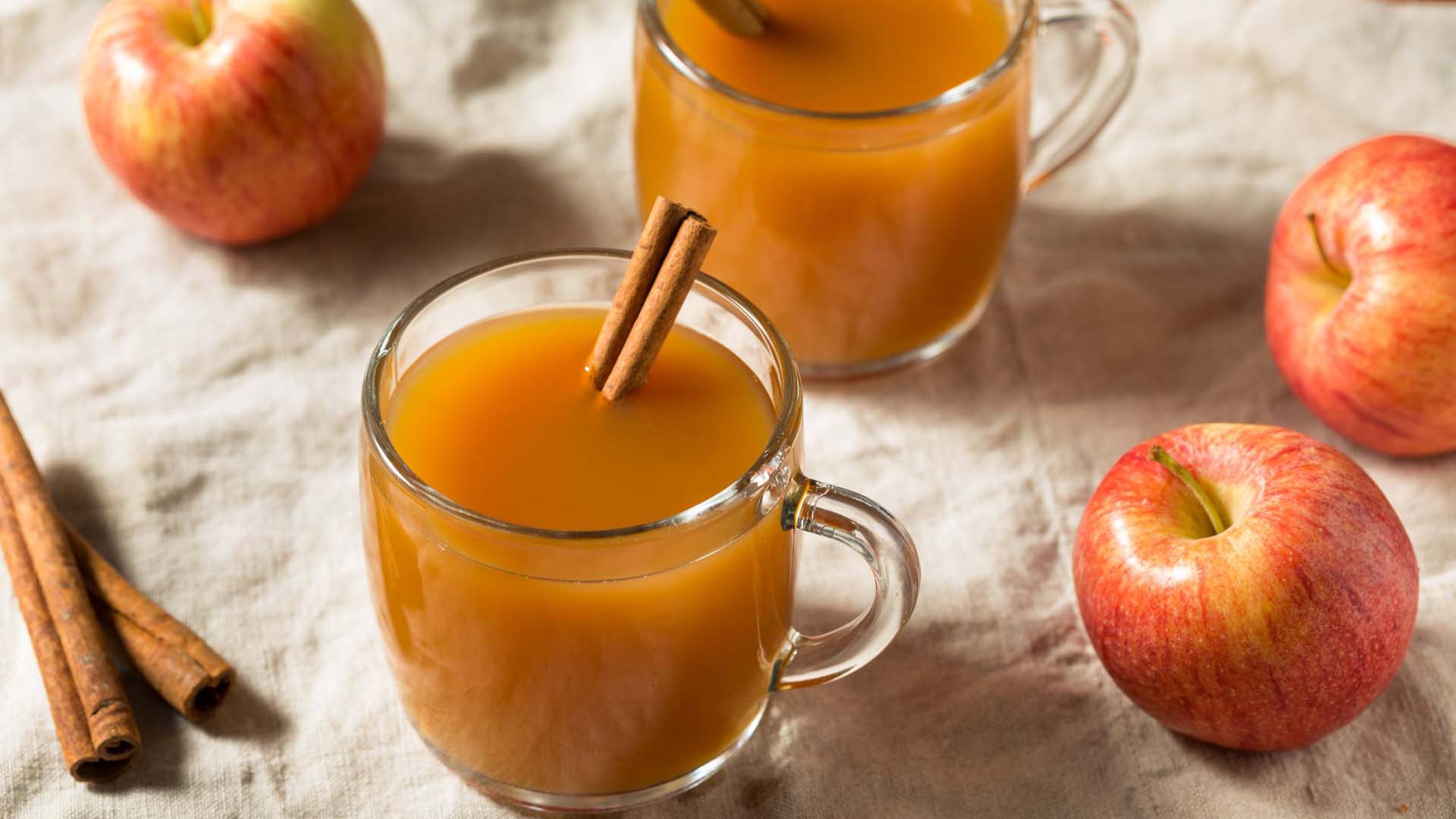 cinnamon, apples and hot apple cider laid out on the table