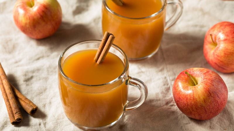 cinnamon, apples and hot apple cider laid out on the table