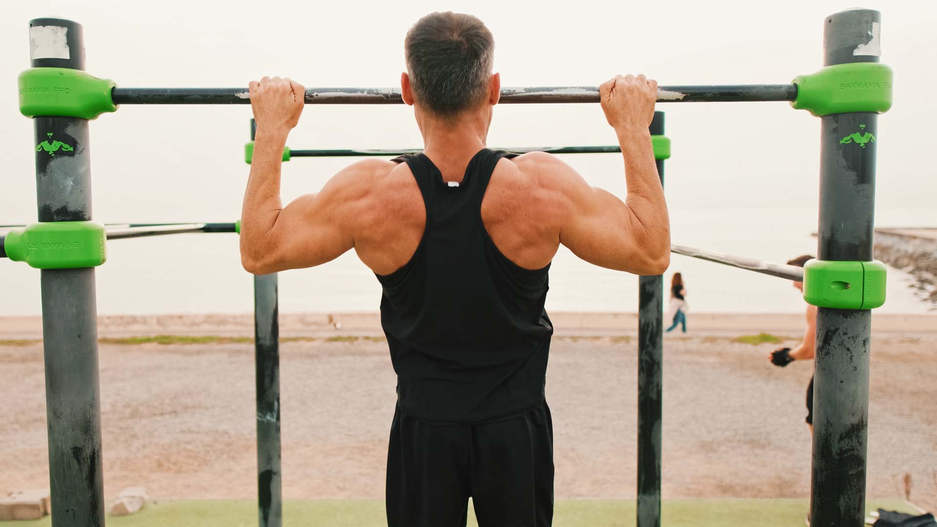 man doing a pull up at the beach