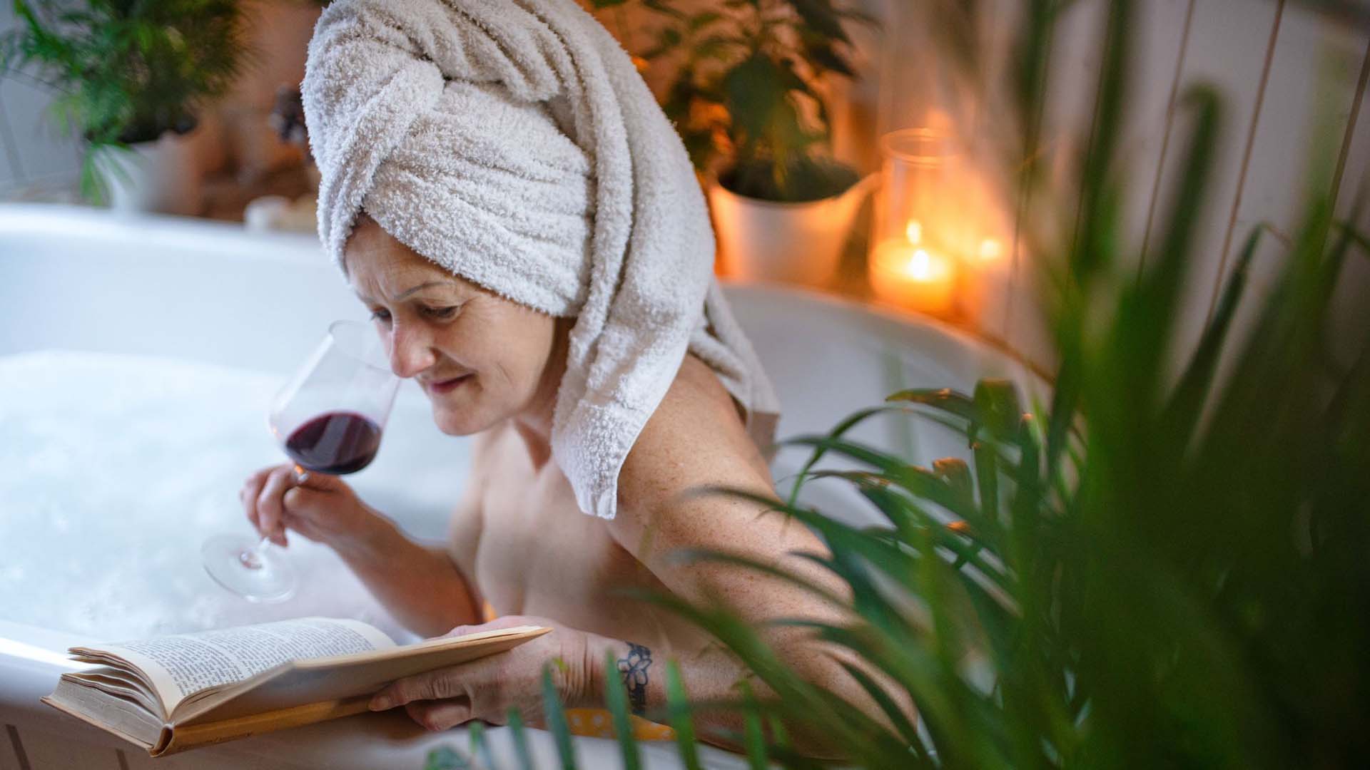 A older woman enjoying a glass of wine in the bath