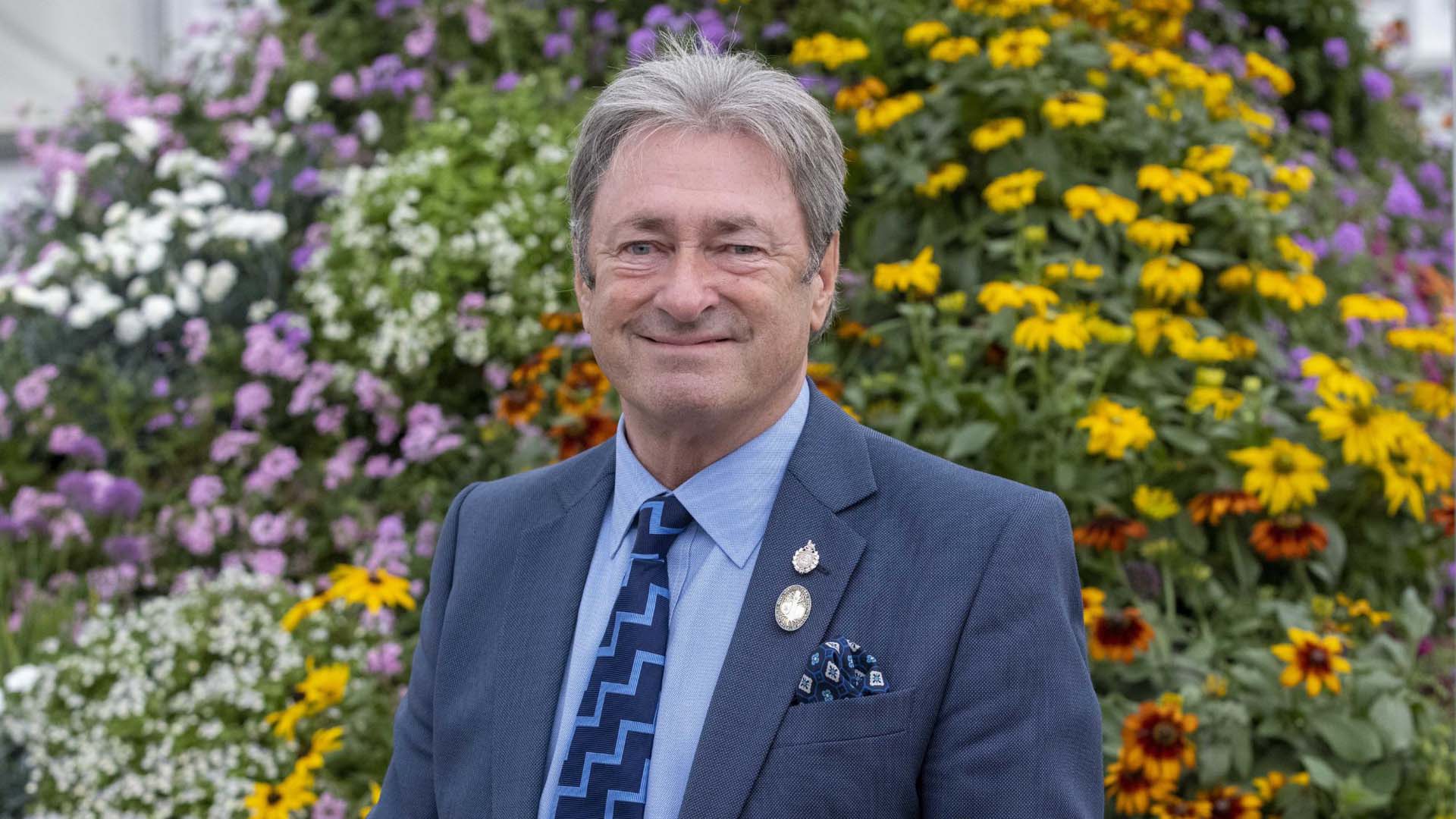 Alan Titchmarsh standing in front of flowers