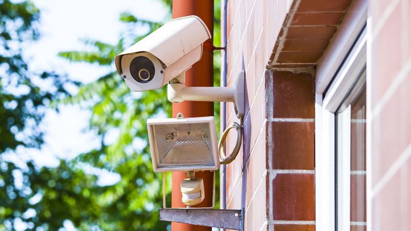 CCTV camera on the house wall near the window with a outside lamp below