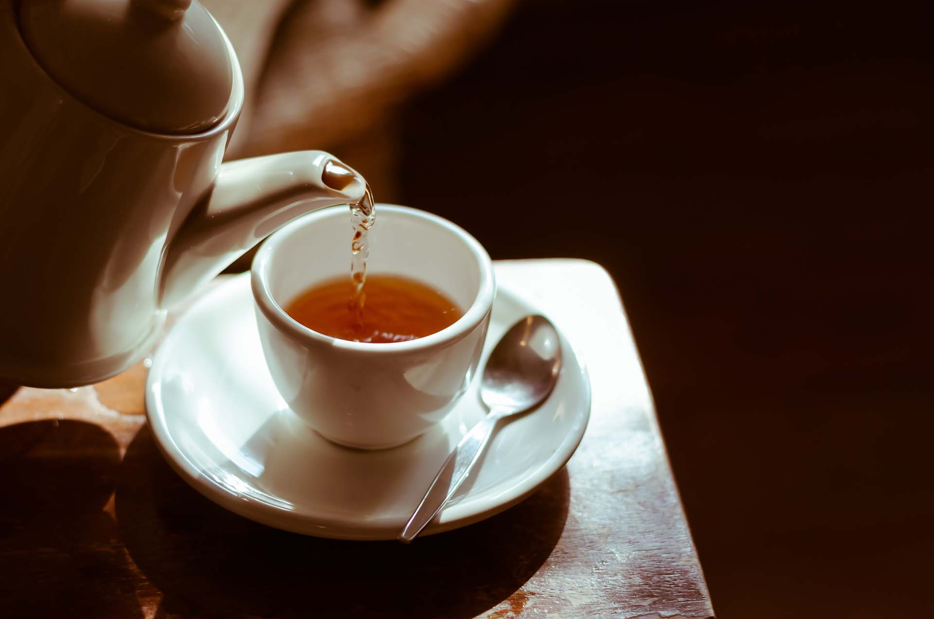 A cup of tea being poured from a teapot