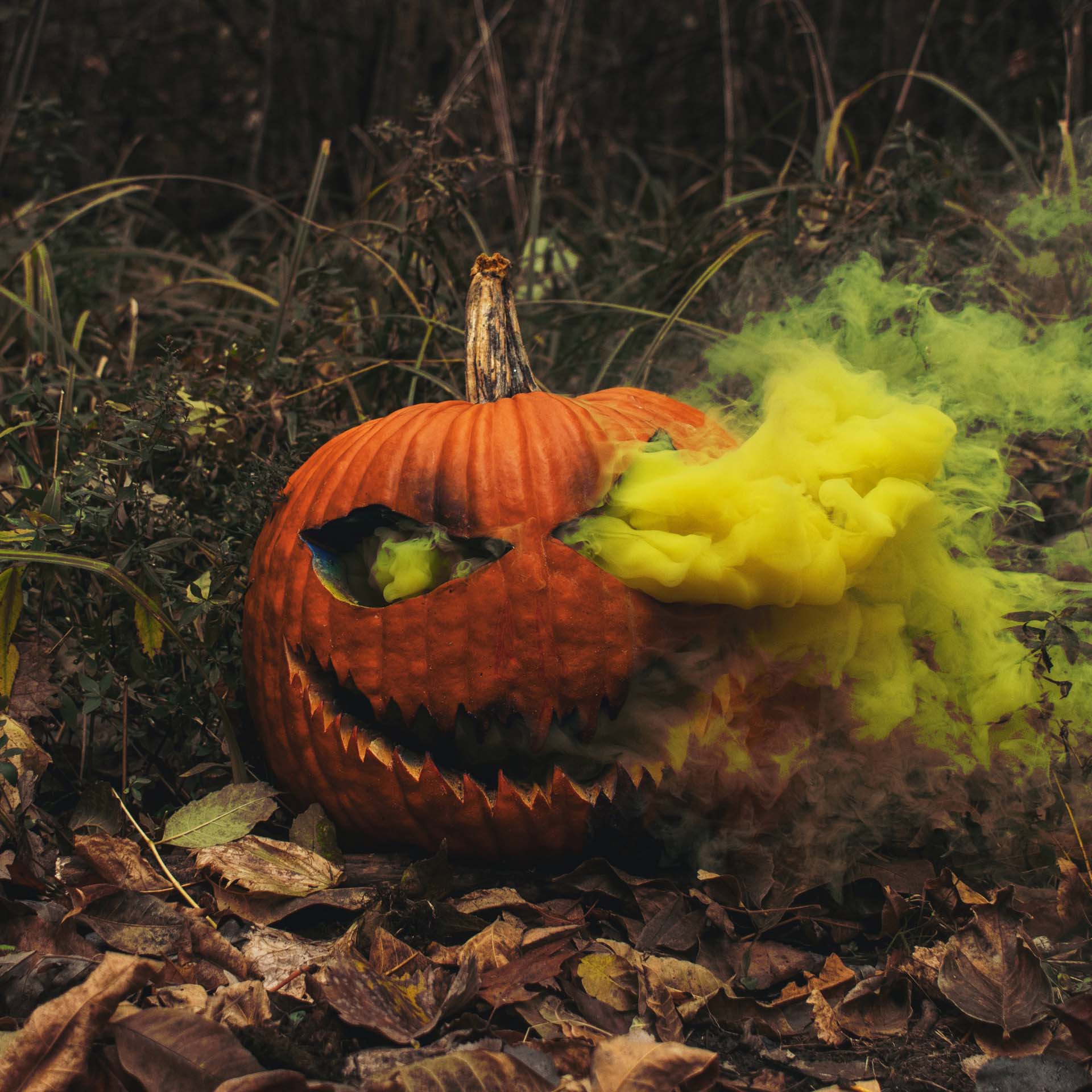 A carved pumpkin with yellow smoke pouring out