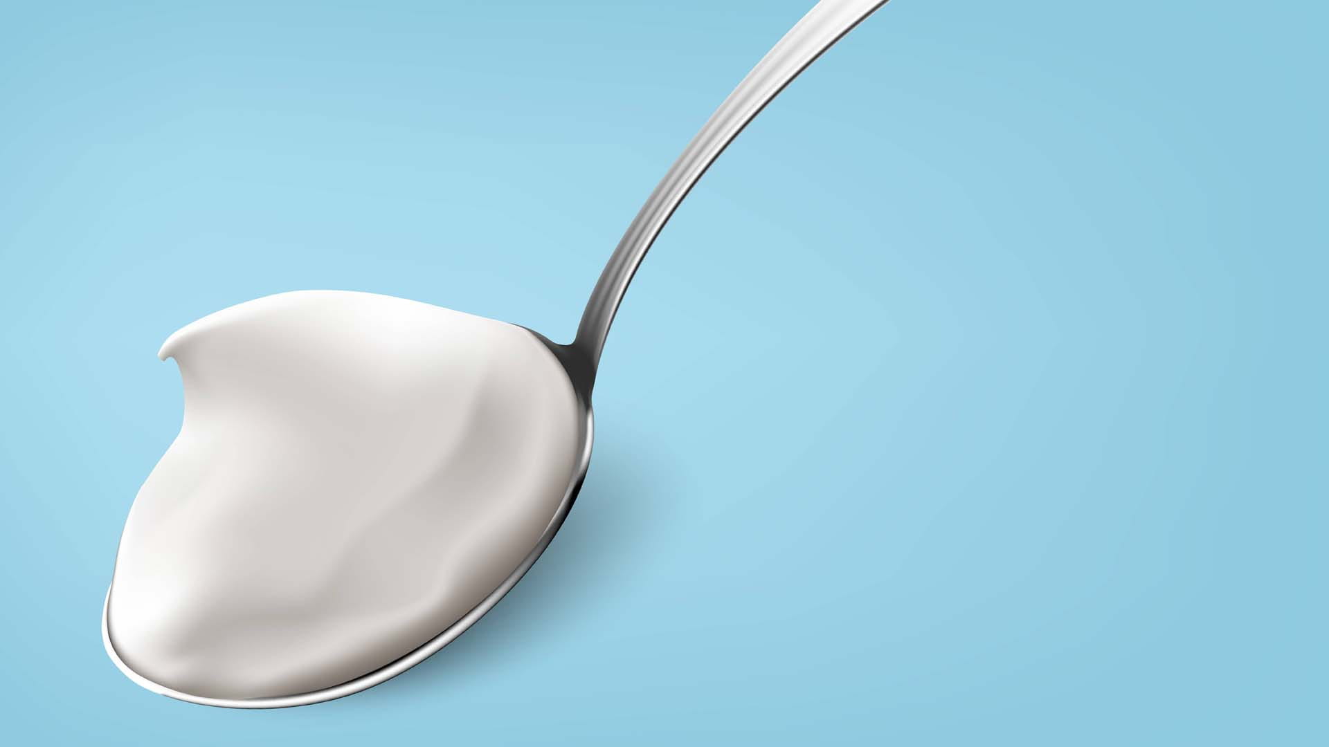 A spoon of yoghurt against a blue background