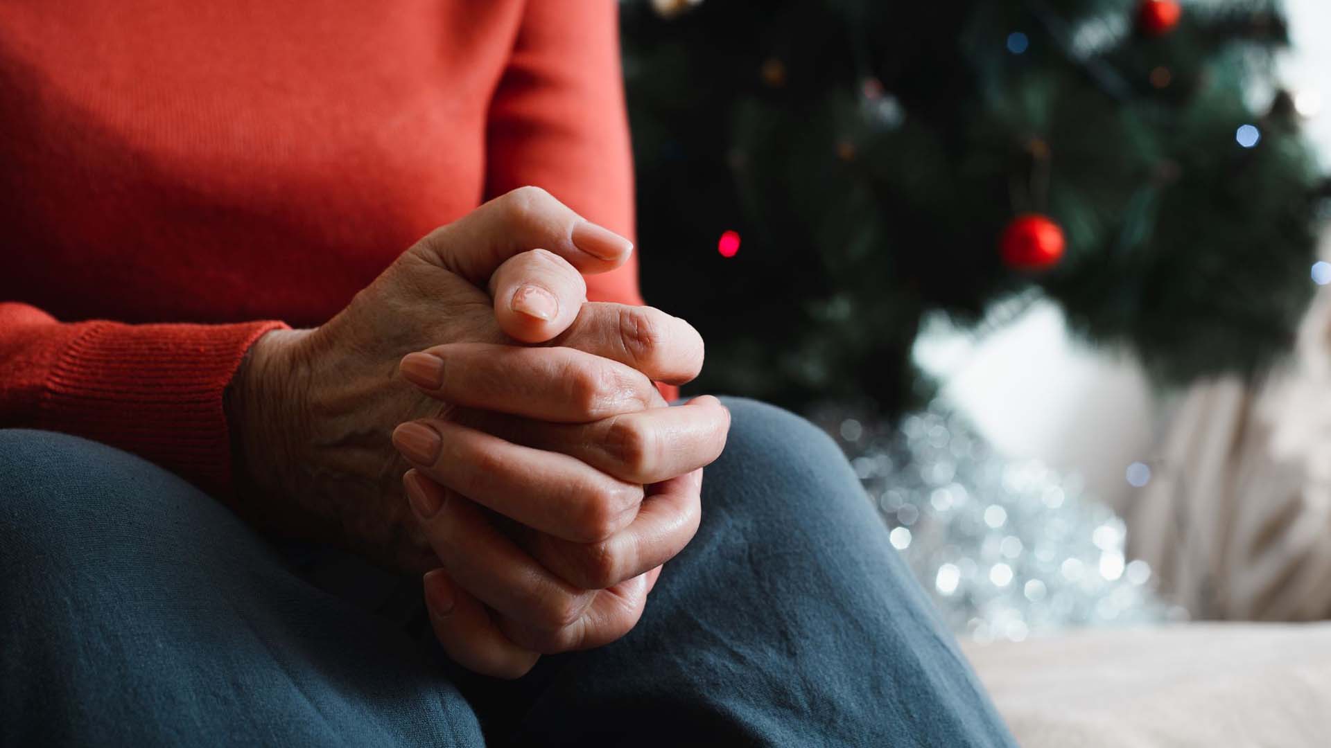 Woman sitting with her hands clenched next to a tree