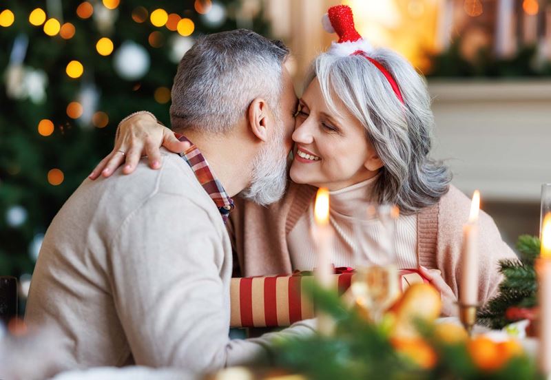 Man kissing a woman at the kitchen table