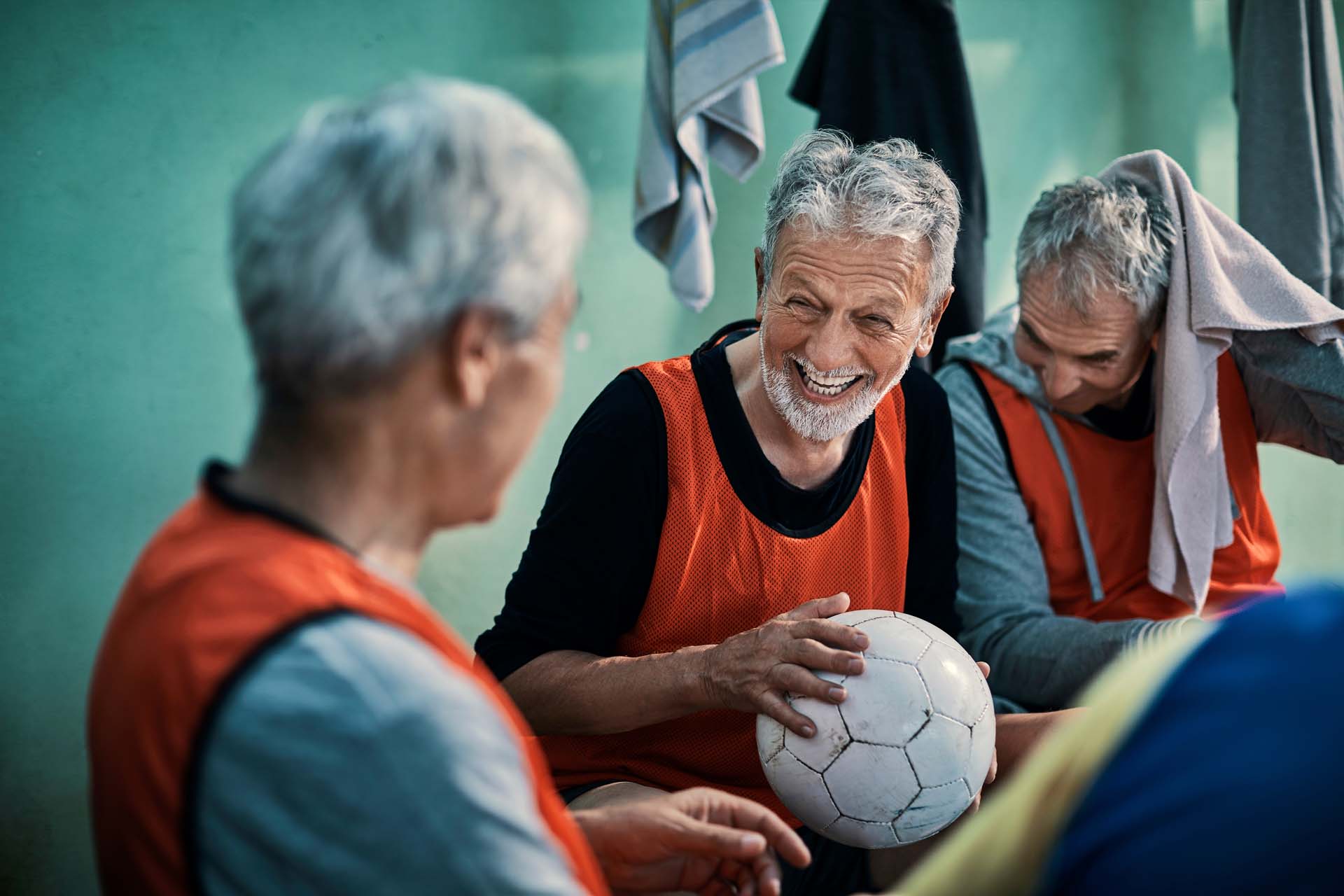 An older group of men chat after playing football