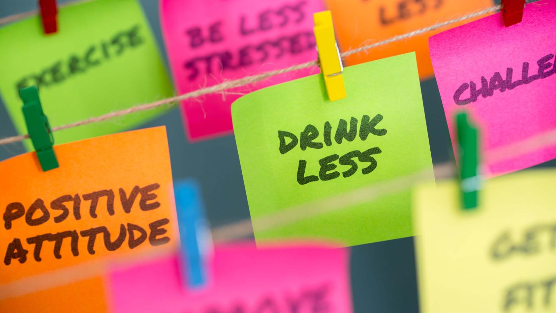Colourful post-it notes pegged to string with goals written on them, such as 'drink less' and 'exercise'