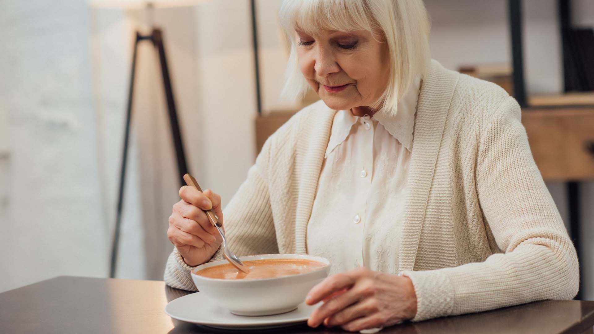 A senior person eating soup to stay warm