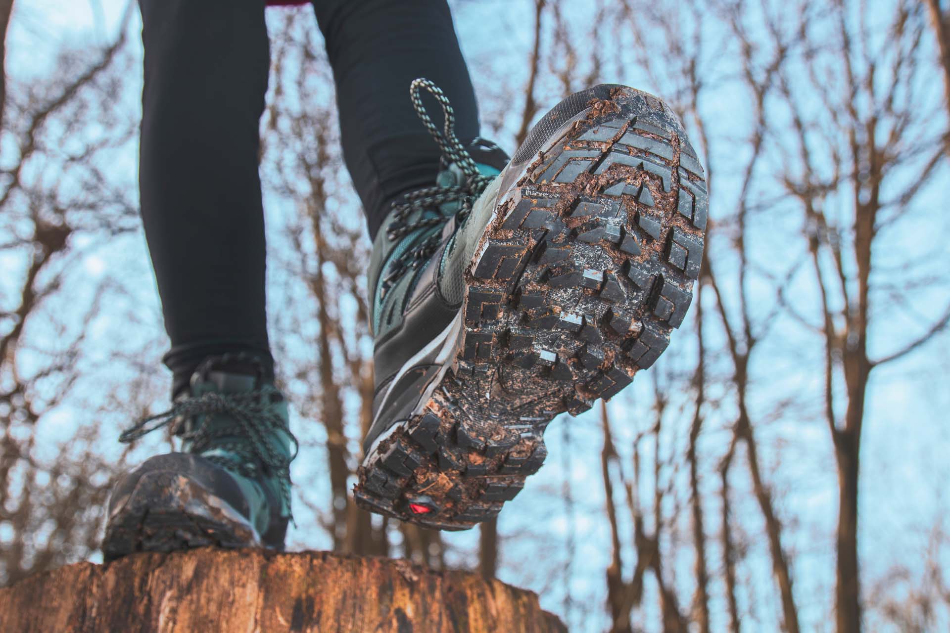 A walker striding out, showing the underneath of a grippy pair of outdoor walking shoes