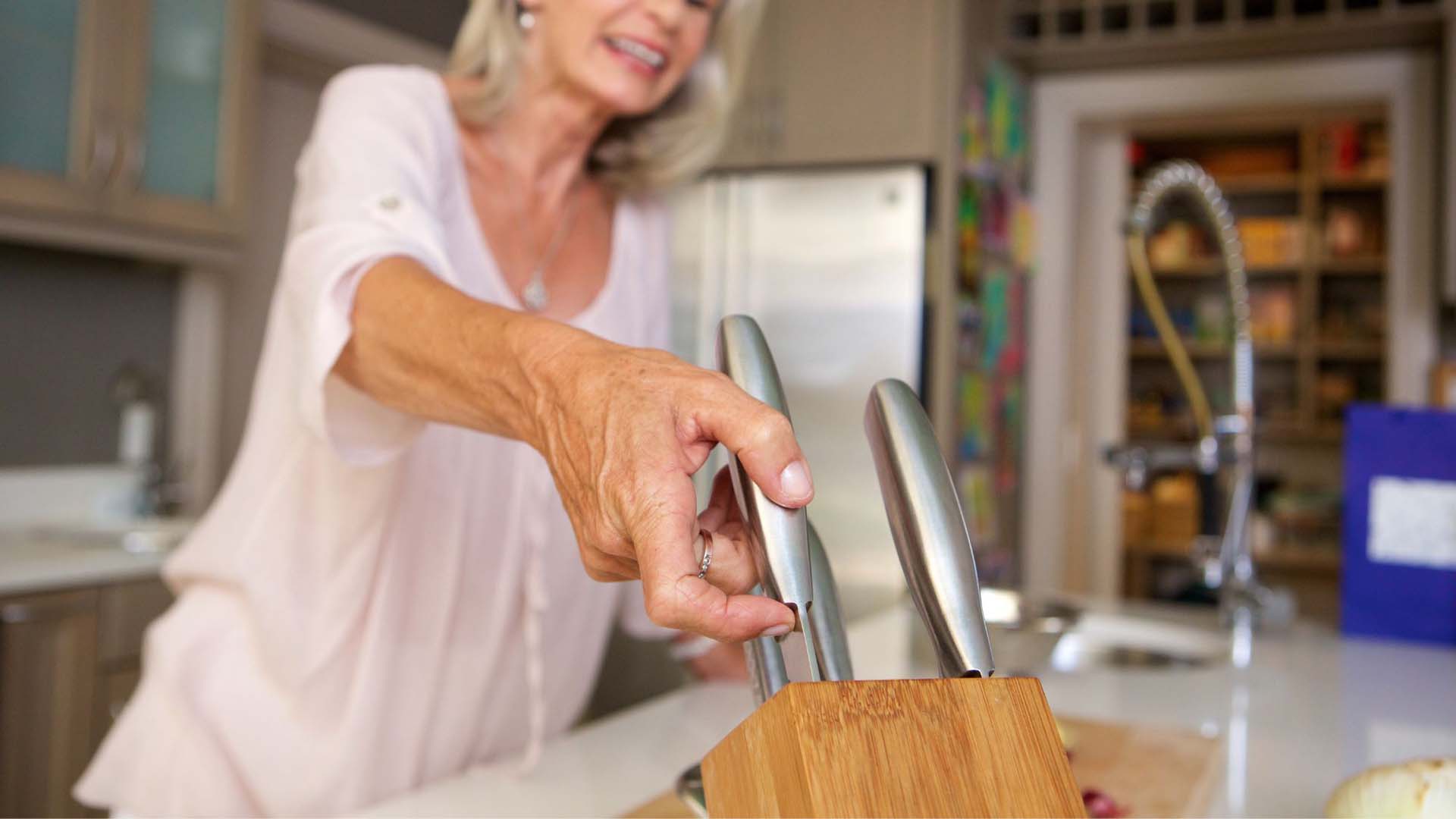 woman reaching for knives from a knife block