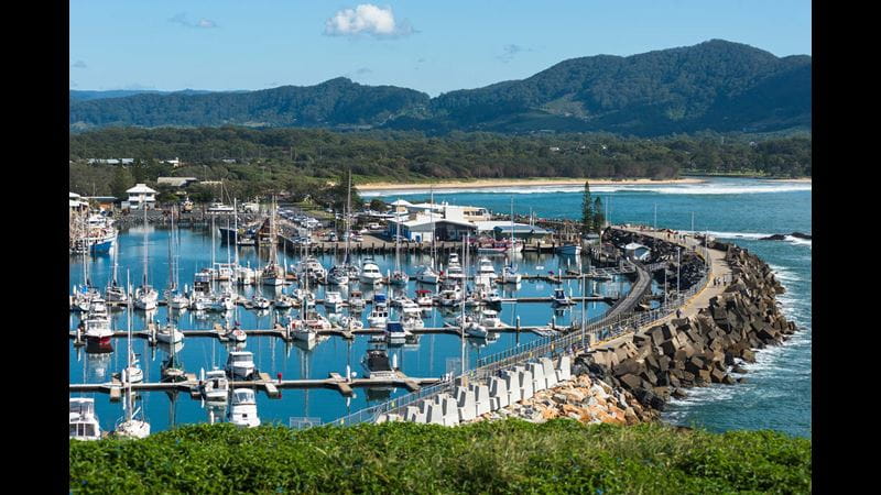 A view over the seaside city of Coff's Harbour, Australia, packed with yachts and pleasure craft with wooded hills in the background.