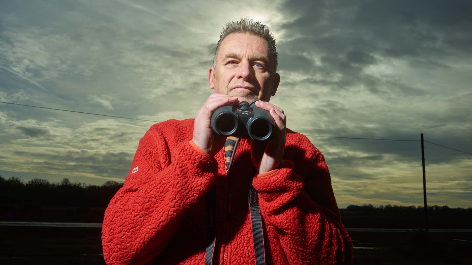Chris Packham holding a pair of binoculars