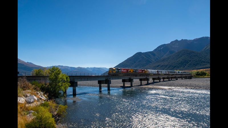 A train crossing a river on a bridge crossing a river in the sunshine