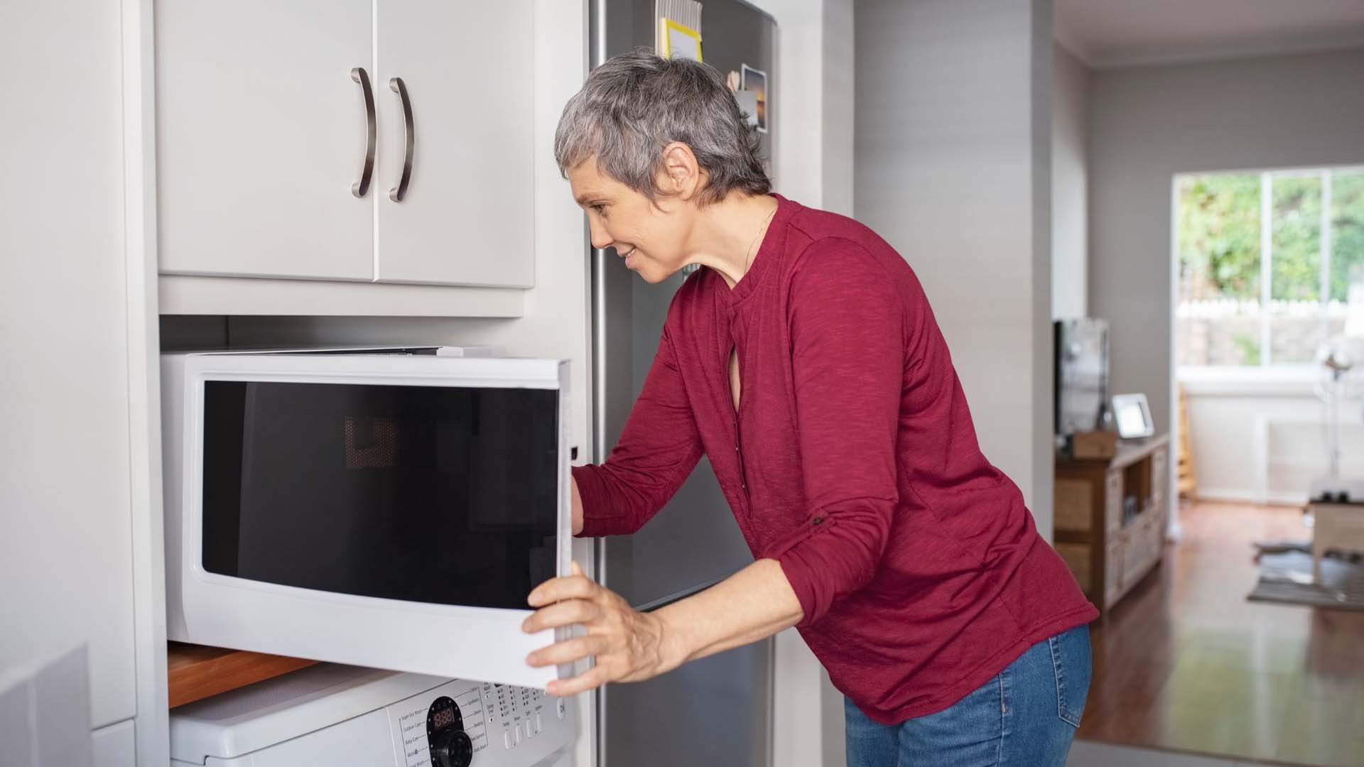 Senior lady putting something in her microwave