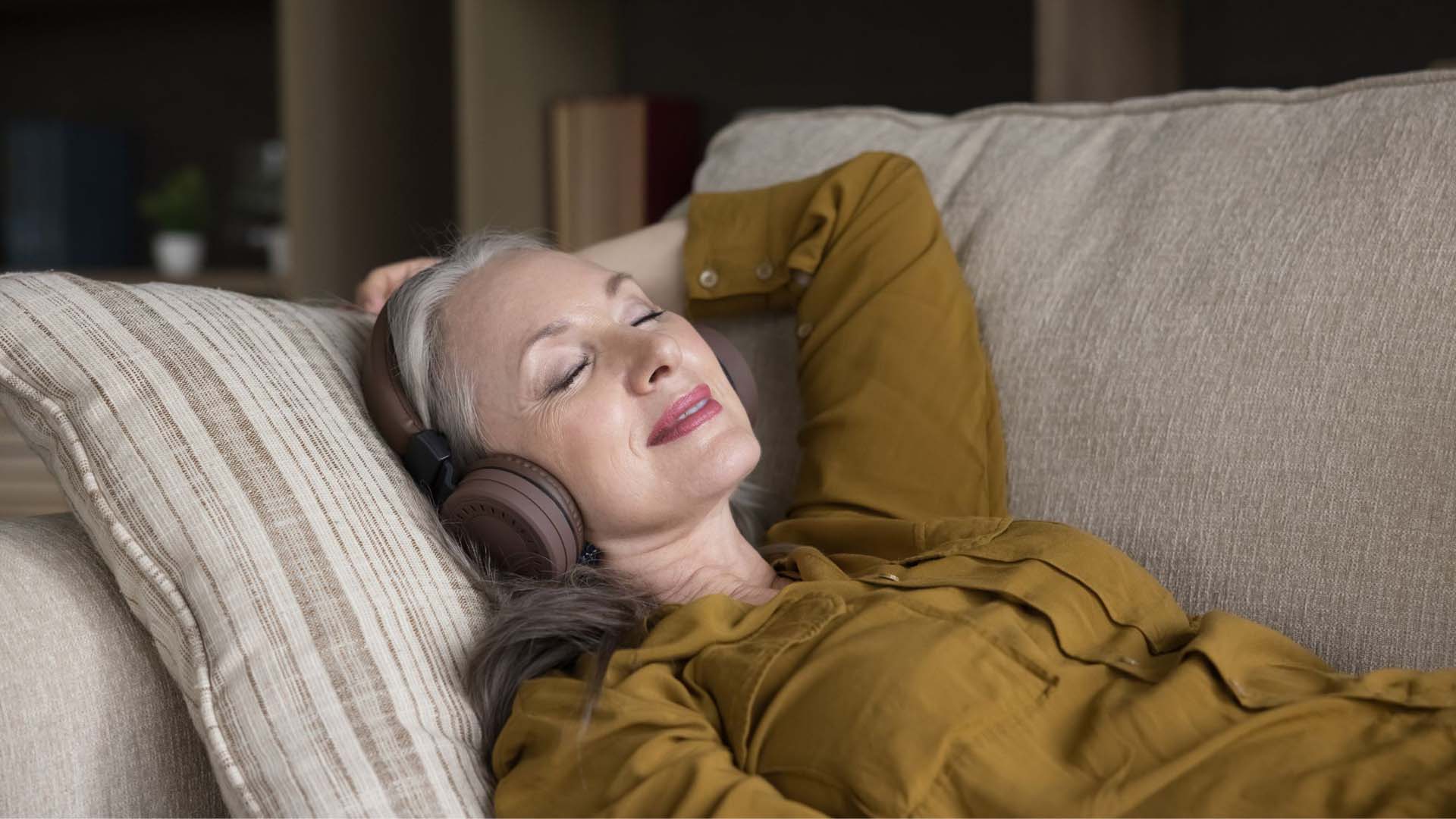 A woman lying down and listening to white noise on wireless headphones