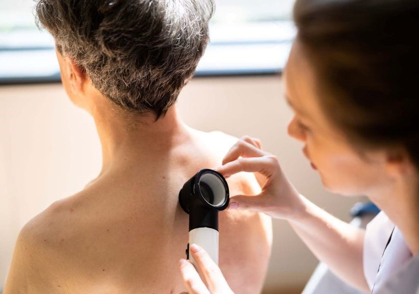 Doctor checking a mole on a mans back