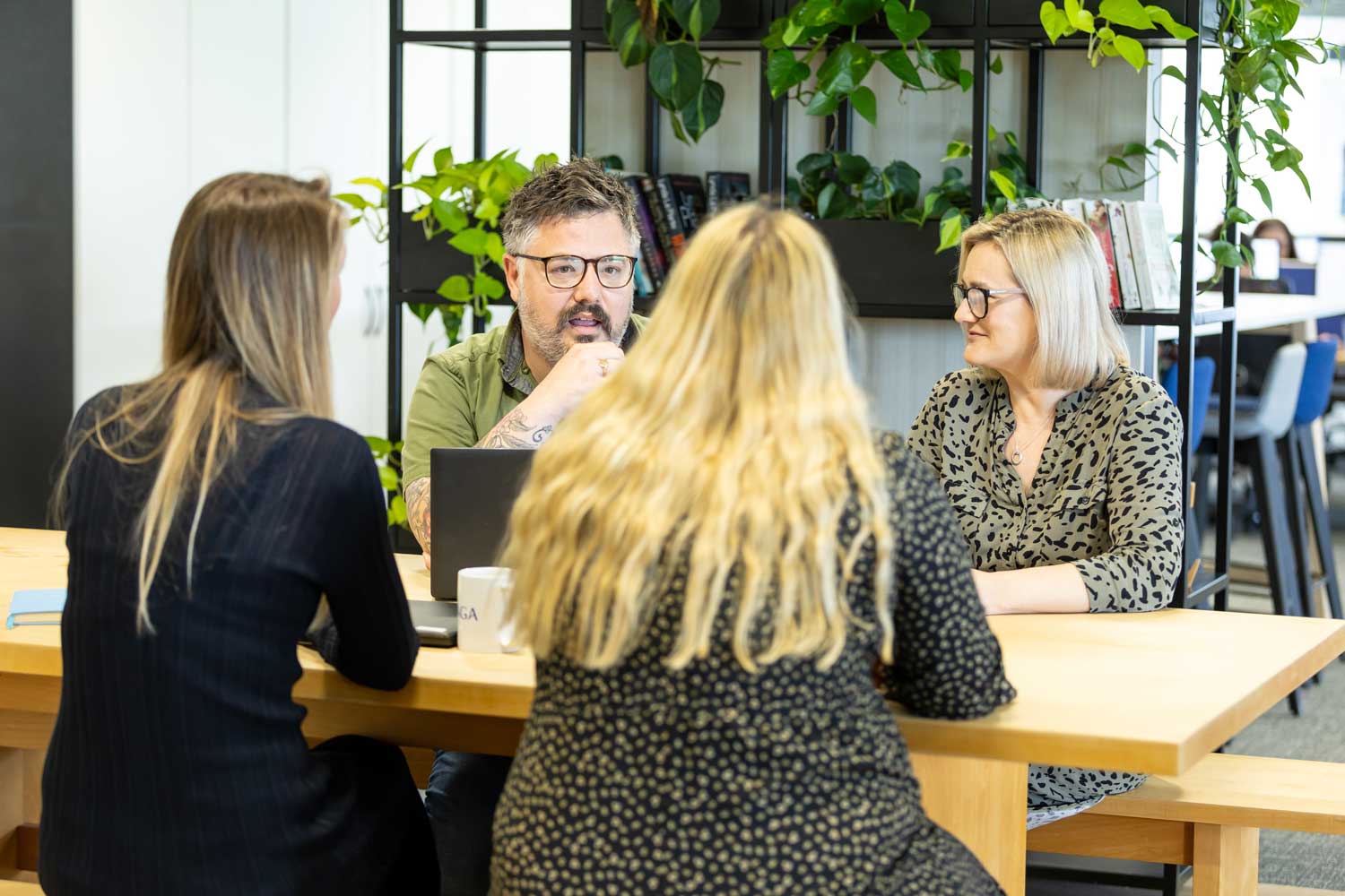 Four people sitting at a desk discussing work