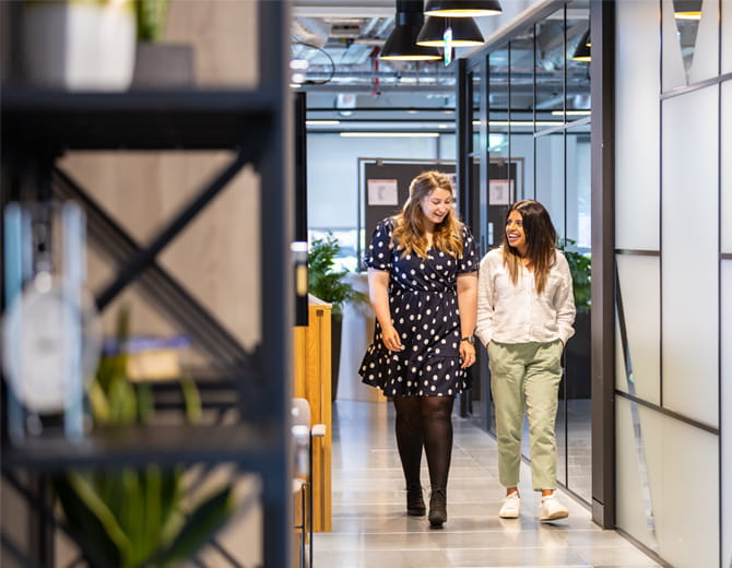 Two people walking through the Saga London office