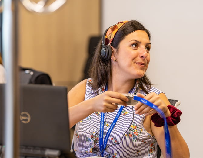 Person at a desk wearing a headset and handing out a Saga work pass