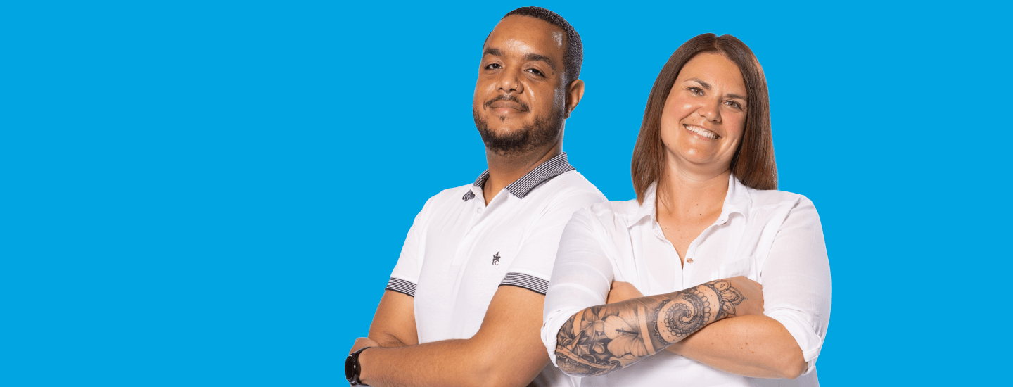 Two people standing back to back with folded arms and smiling on a blue background