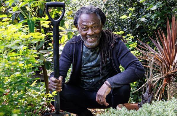 Danny Clarke with a spade kneeling in a garden bed
