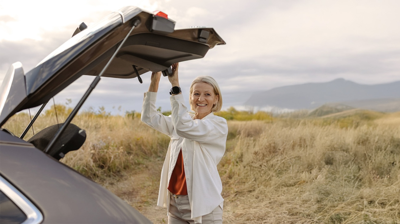 A woman in a rural setting closing the boot of her car