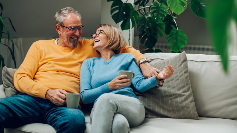 A happy senior couple sitting on a sofa with a cup of tea