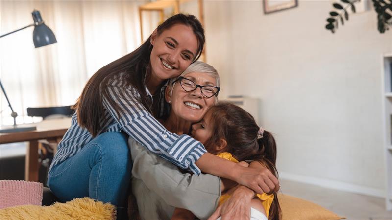 Person hugging a child in a cozy living room setting.