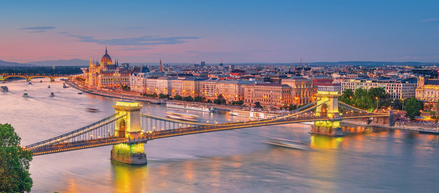  city skyline and illuminated bridge over a river at sunset