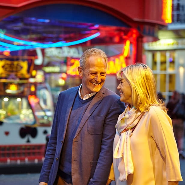 A mature couple walking through a fun fair holding hands