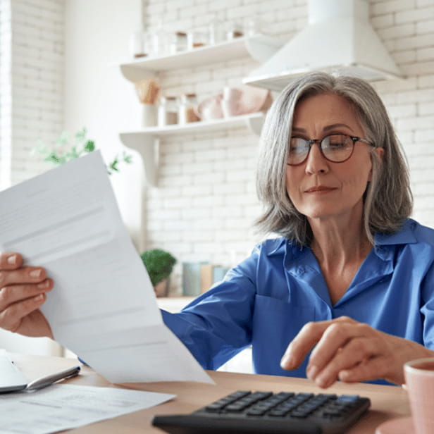 Older person sitting at a desk with papers and a calculator