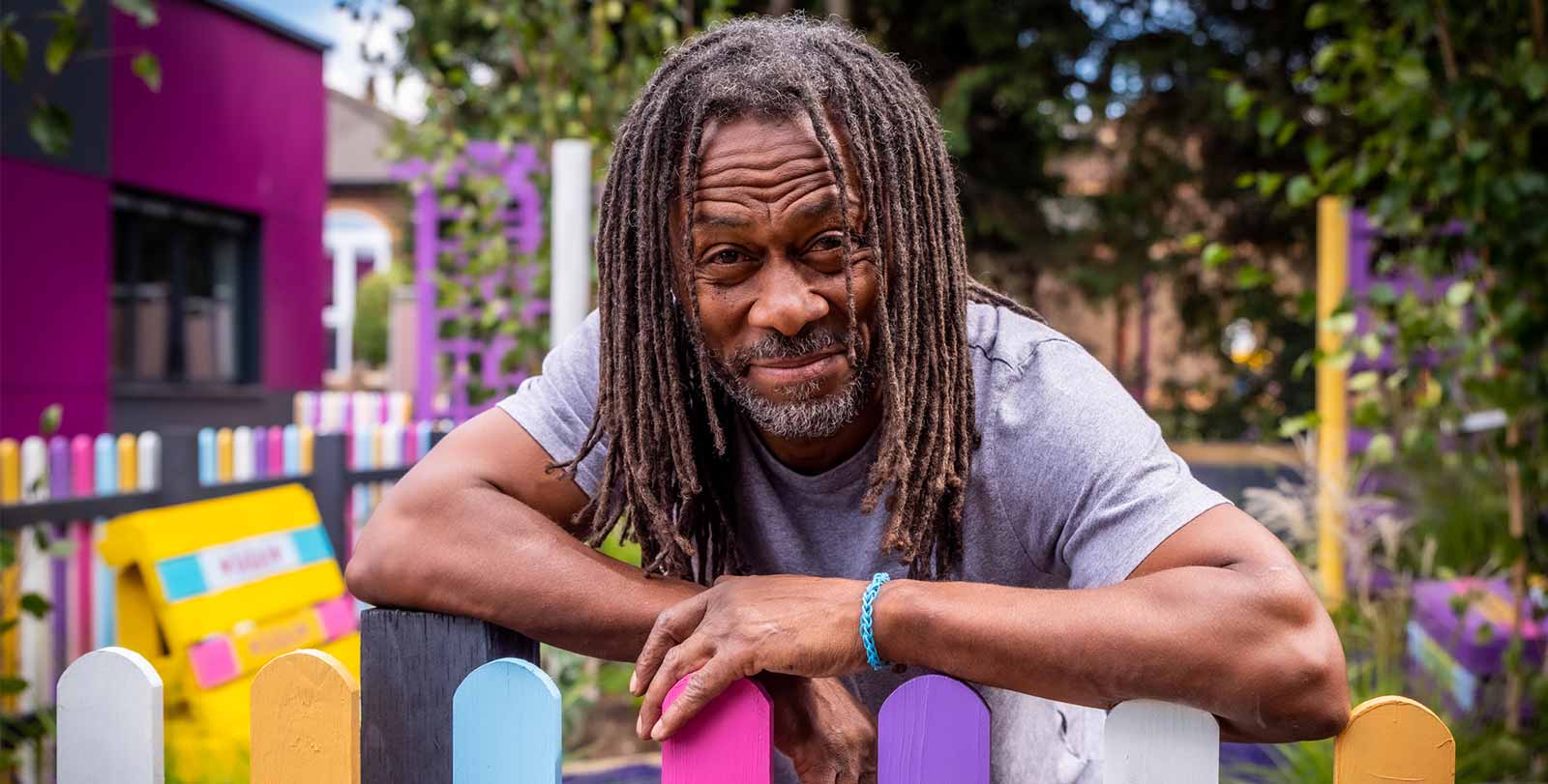 Danny Clarke leaning on a colourful picket fence