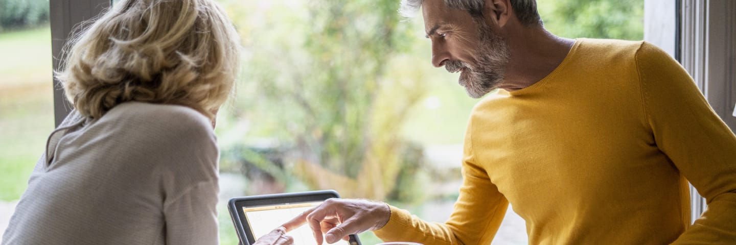 Person in a yellow top pointing at a screen while talking to a second person