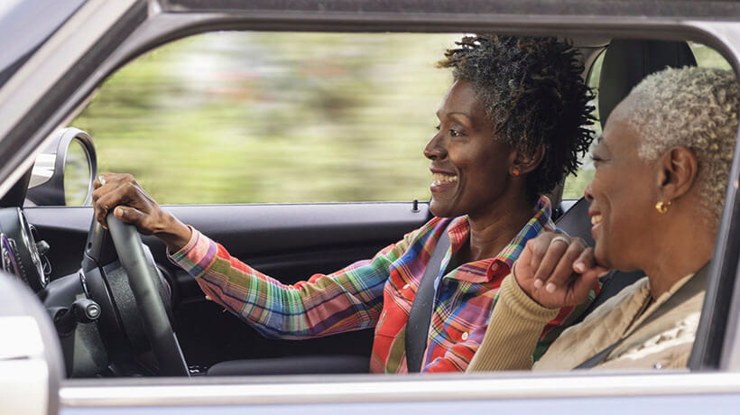 Two smiling women driving with the window down