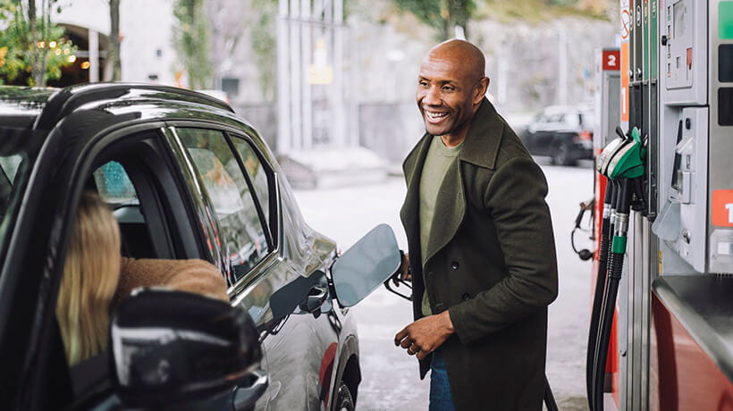 A mature man talking to a woman while refuelling car while at petrol station