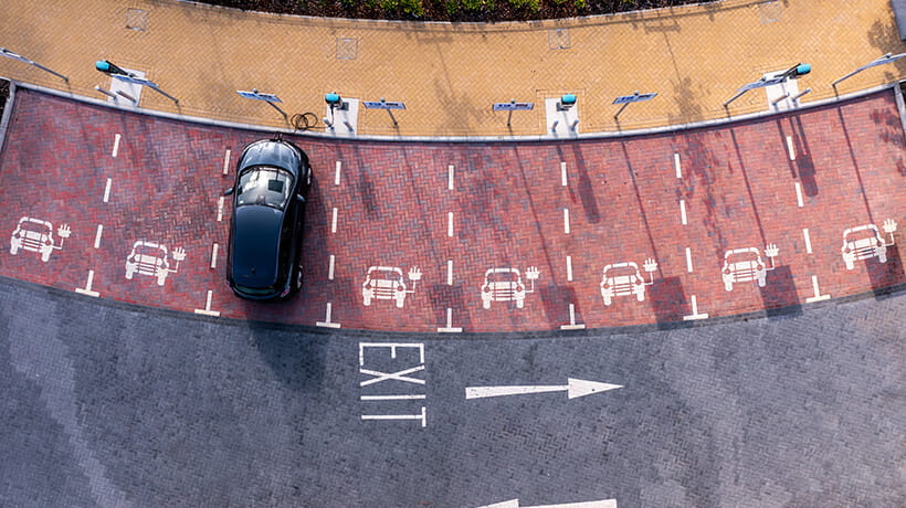 An aerial view directly above an electric vehicle charging station with electric car charging in a parking space