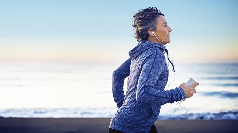 A mature woman running next to the sea