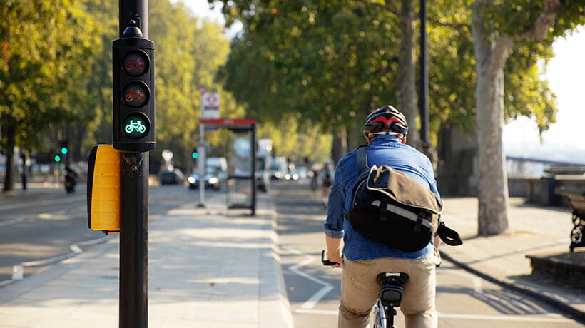 Senior man cycling away from camera in bike lane on the Embankment London