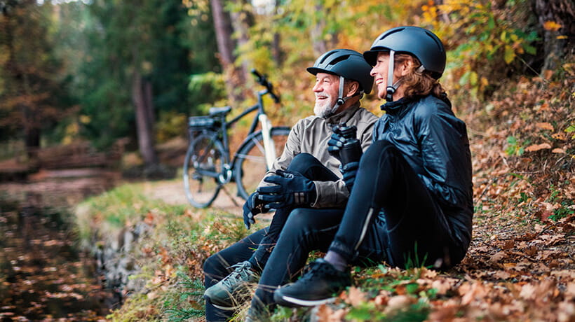 A couple of cyclists relaxing next to a river in autumn