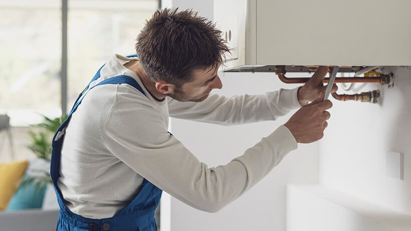 A plumber servicing a home boiler