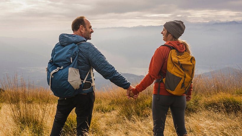 A mature couple holding hands while hiking