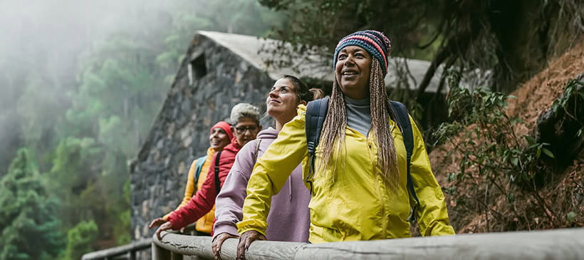 Group of women with different ages and ethnicities having fun walking in foggy forest