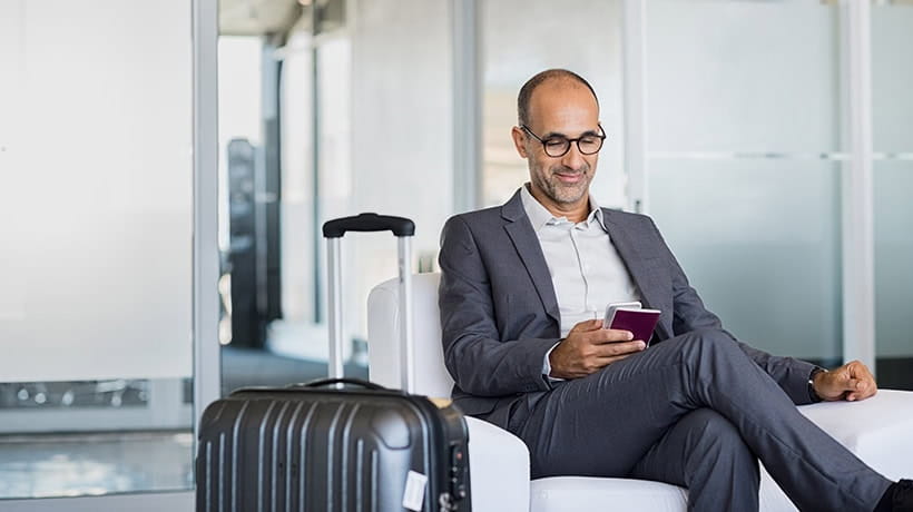 Mature man using mobile phone at the airport in the lounge area.
