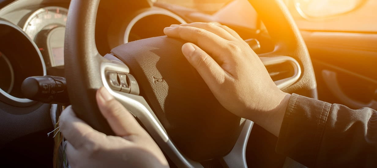 Close up of a male hand on a steering wheel ready to sound the car horn.