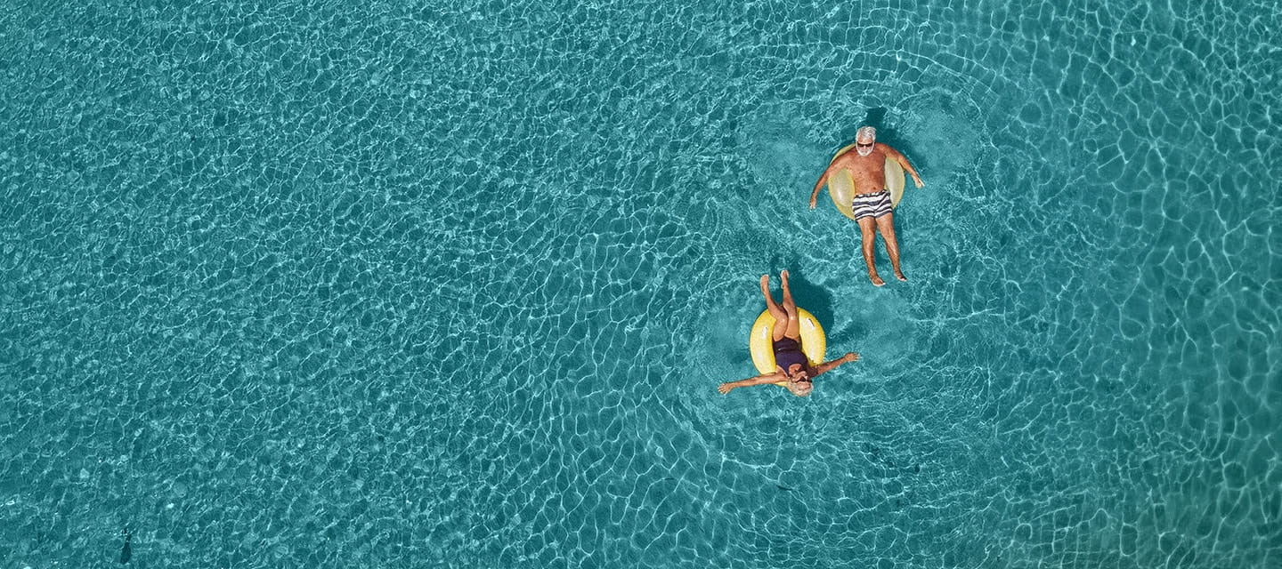 A mature couple relaxing in a swimming pool on a sunny day.
